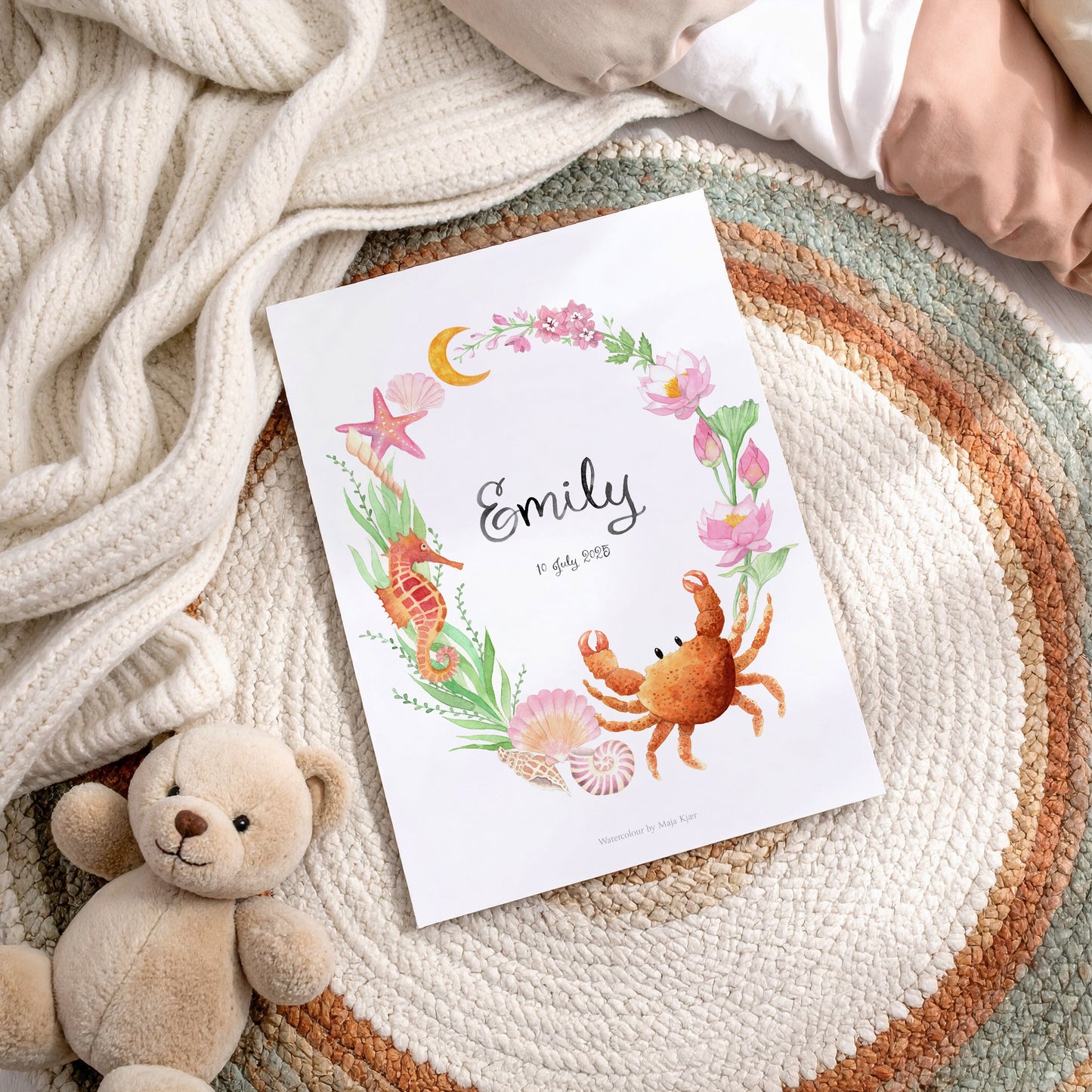 Baby name poster with ocean-themed illustrations and 'Emily' on a textured surface with a teddy bear.