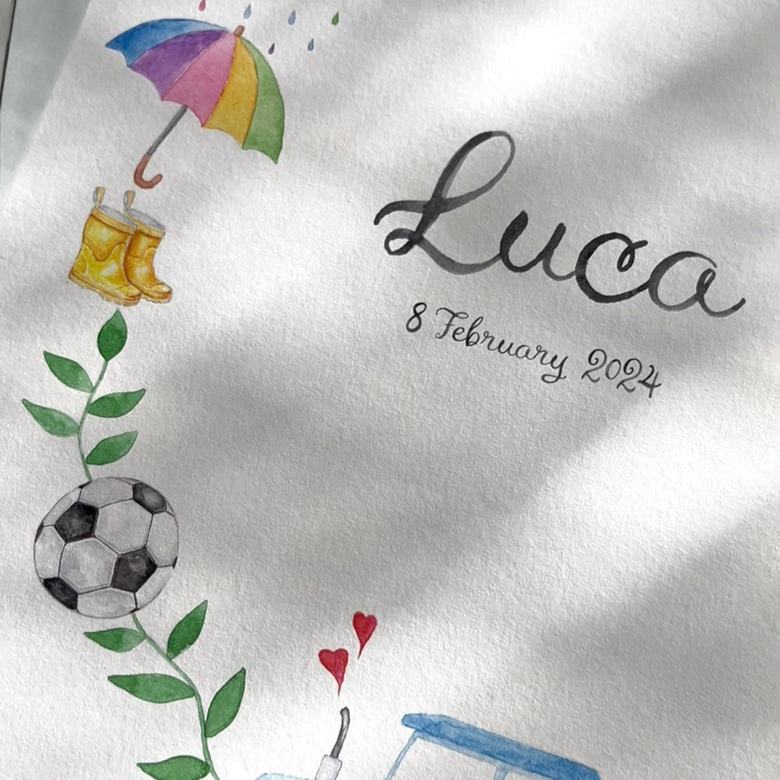 Baby name print with illustrations of a tractor, umbrella, rain boots, soccer ball, and heart, along with the name 'Luca' and date.