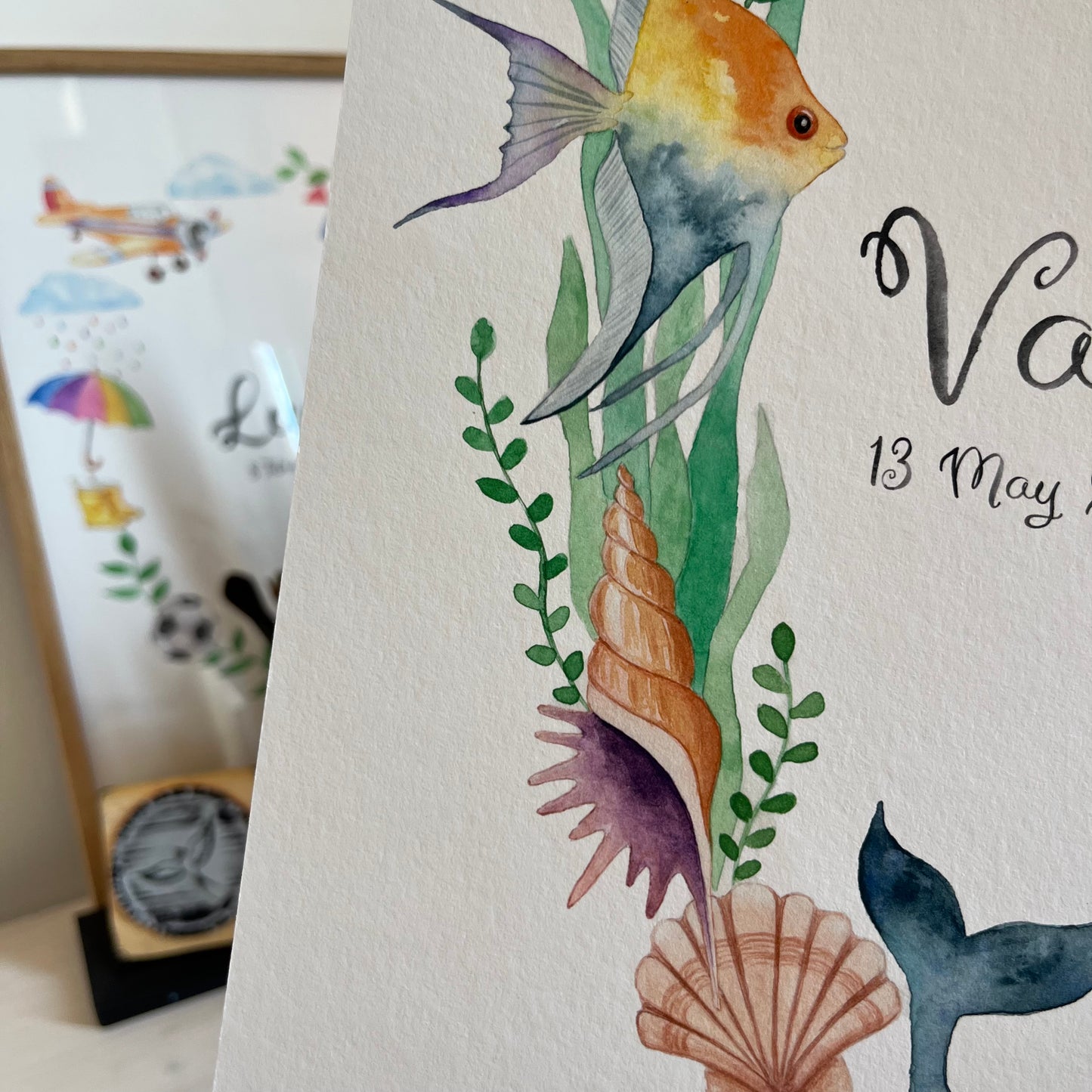 Closeup of Children's name poster with underwater-themed illustrations including fish, shells, and seaweed on a white background.