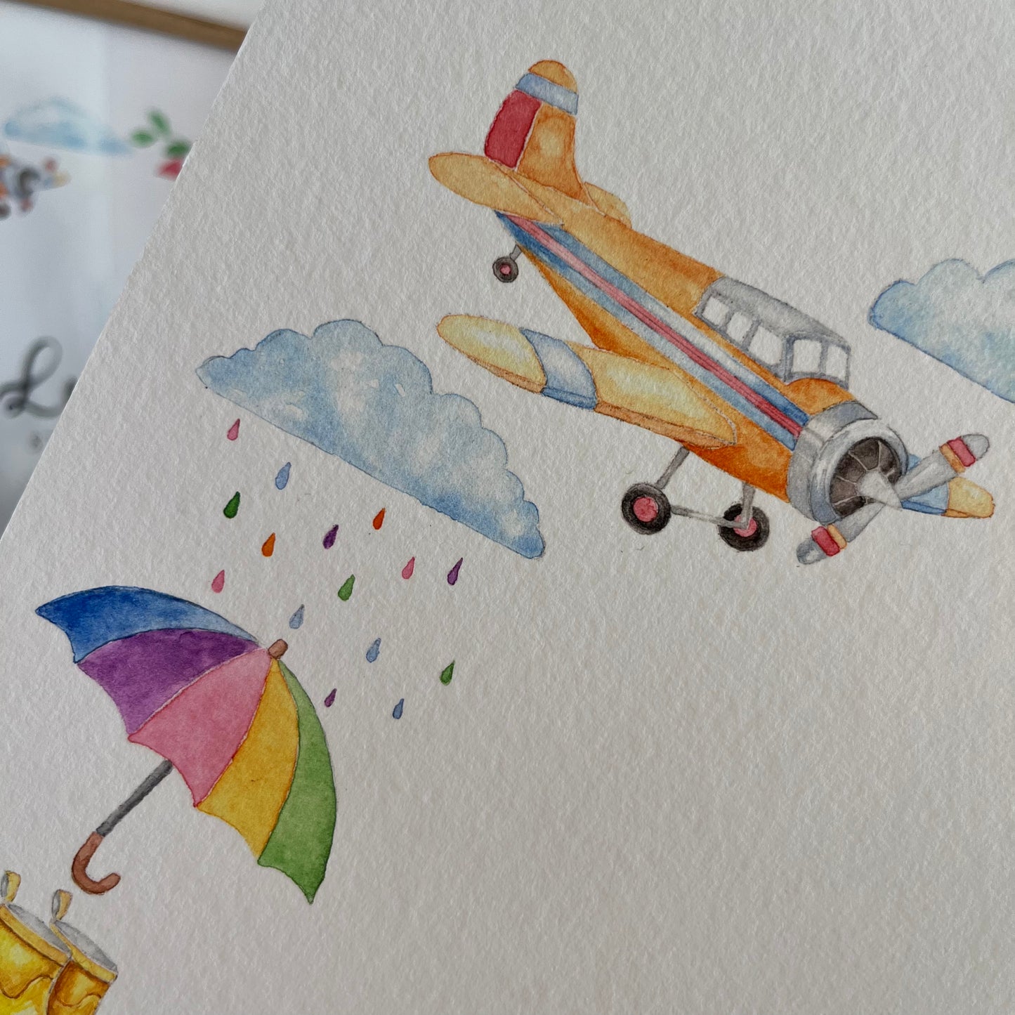 Custom name poster for boys, closeup of illustration of a yellow airplane and colorful umbrella on textured paper.