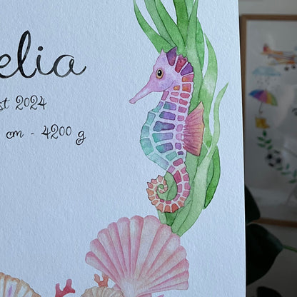 A close-up of a white baby shower card featuring watercolor illustrations of a seahorse, starfish, seashells, and green seaweed, with partial black script text on the left.