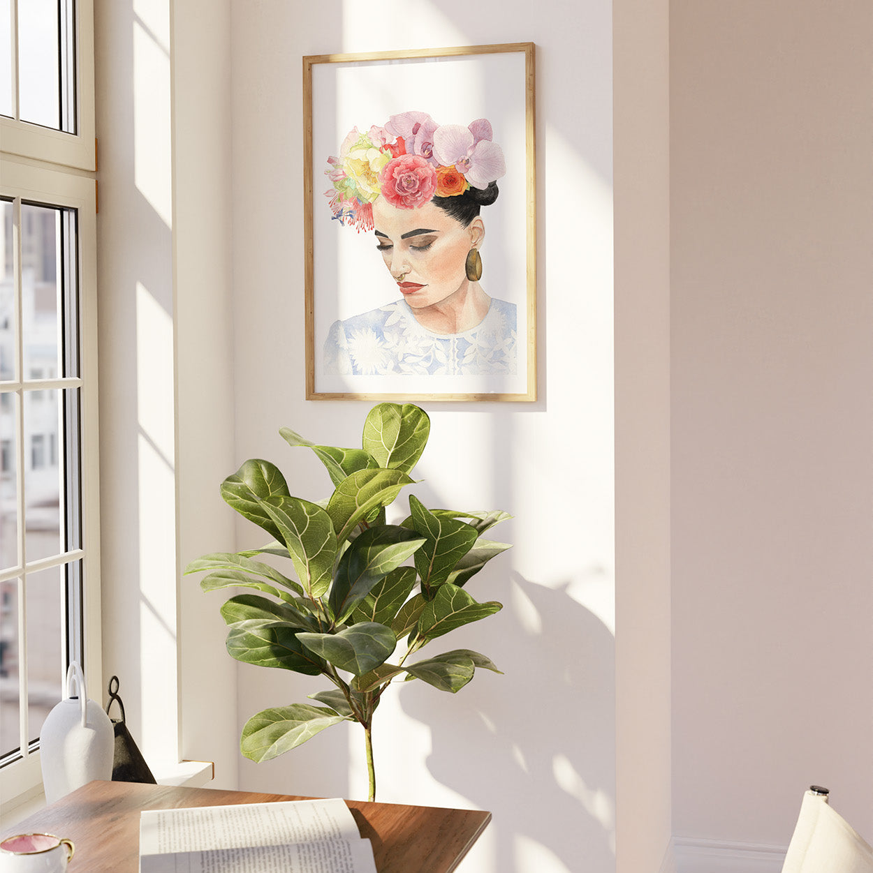 Framed artwork of a woman with flowers in her hair on a wall next to a window.