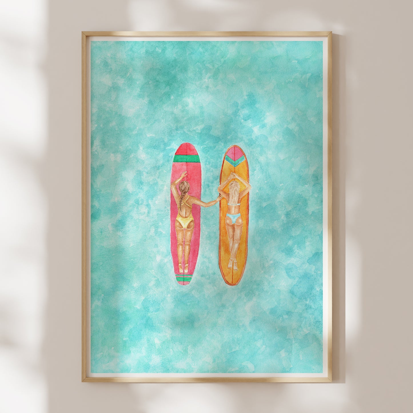 Framed artwork of two women on surfboards against a turquoise background