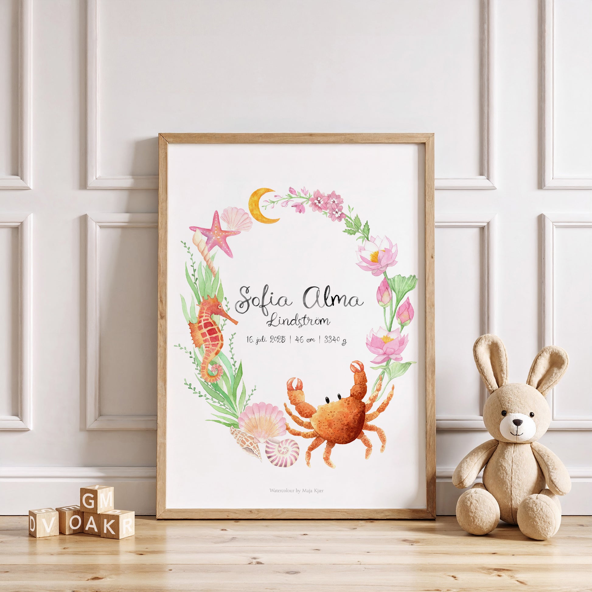 Framed children's artwork with sea-themed design and teddy bear on wooden floor.