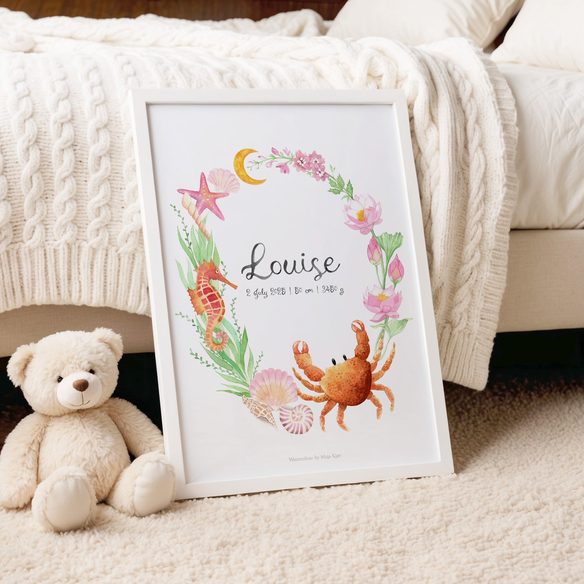Framed artwork with 'Louise' and sea-themed illustrations on a carpeted floor with a teddy bear.
