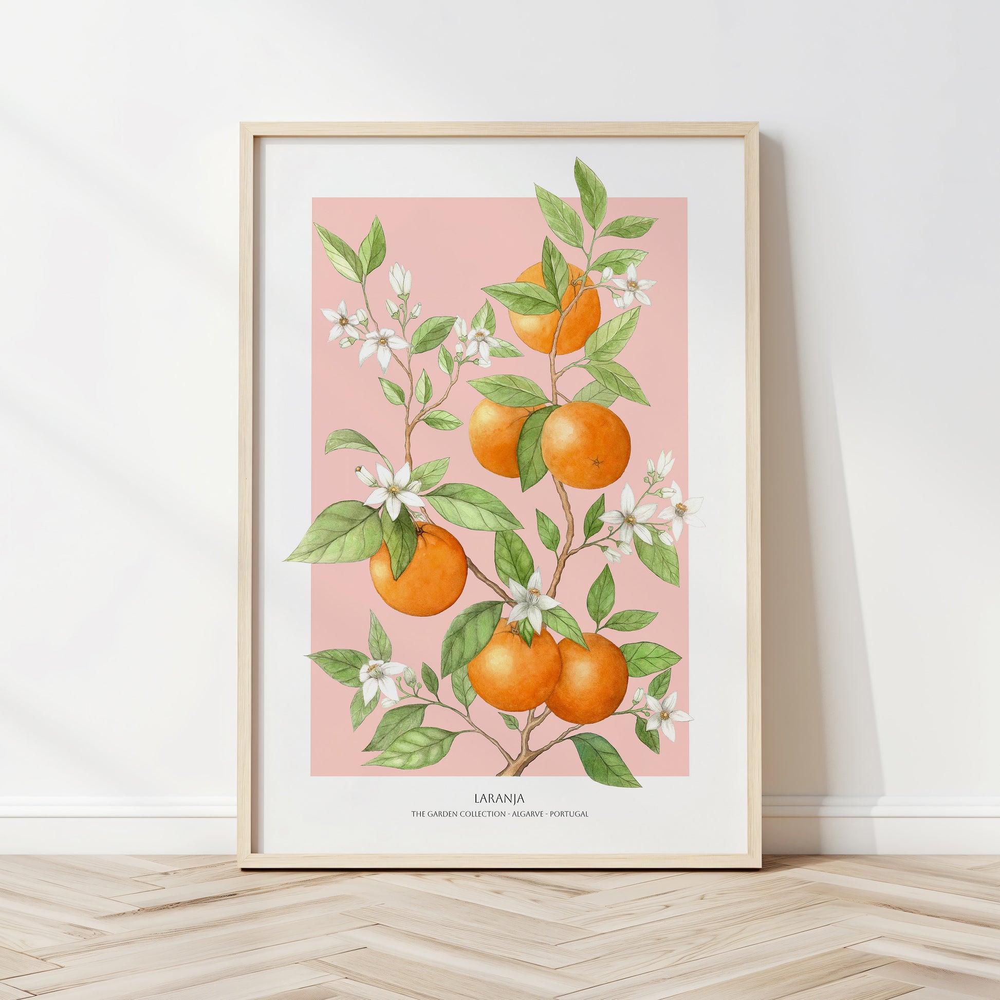 Framed artwork of oranges and leaves on a pink background