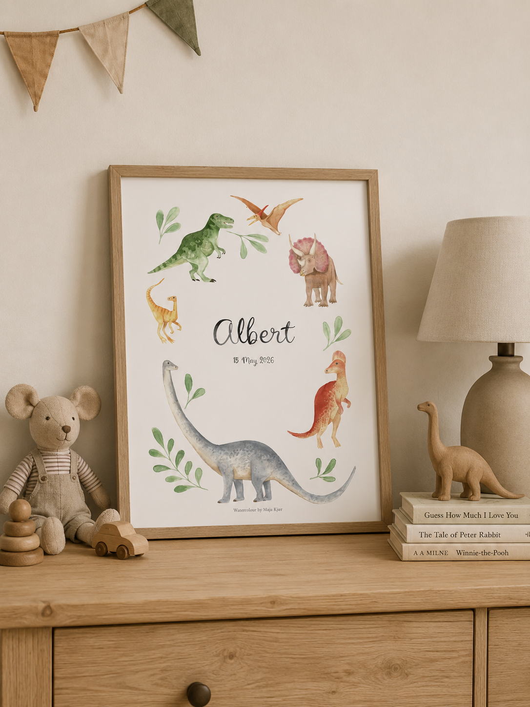 Framed dinosaur print on a wooden dresser with toys and books.