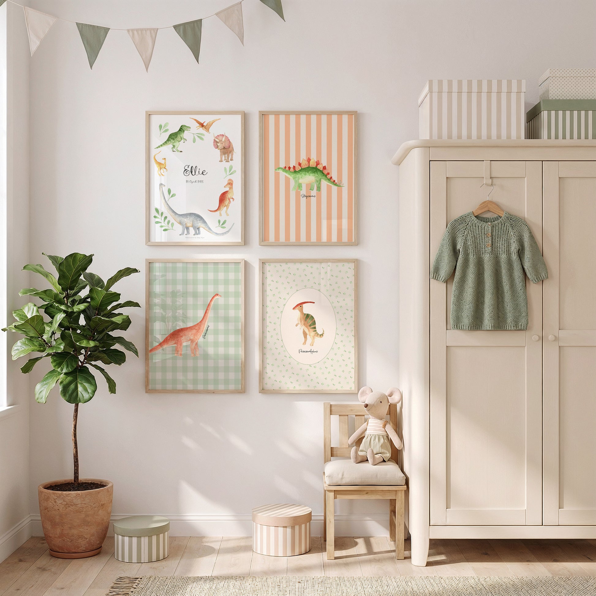 A styled children's room corner featuring four framed dinosaur-themed art prints on a white wall, next to a cream-colored wooden wardrobe with a green knit dress hanging on the door, a small wooden chair with a plush toy, a potted plant, and a string banner.