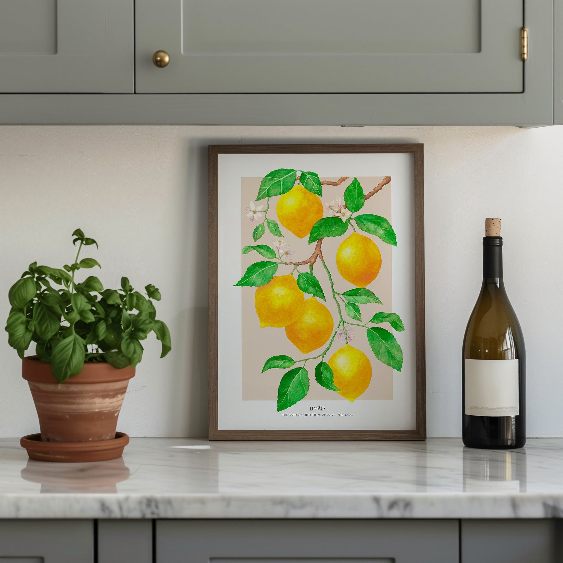 Framed artwork of lemons on a kitchen counter with a plant and wine bottle.