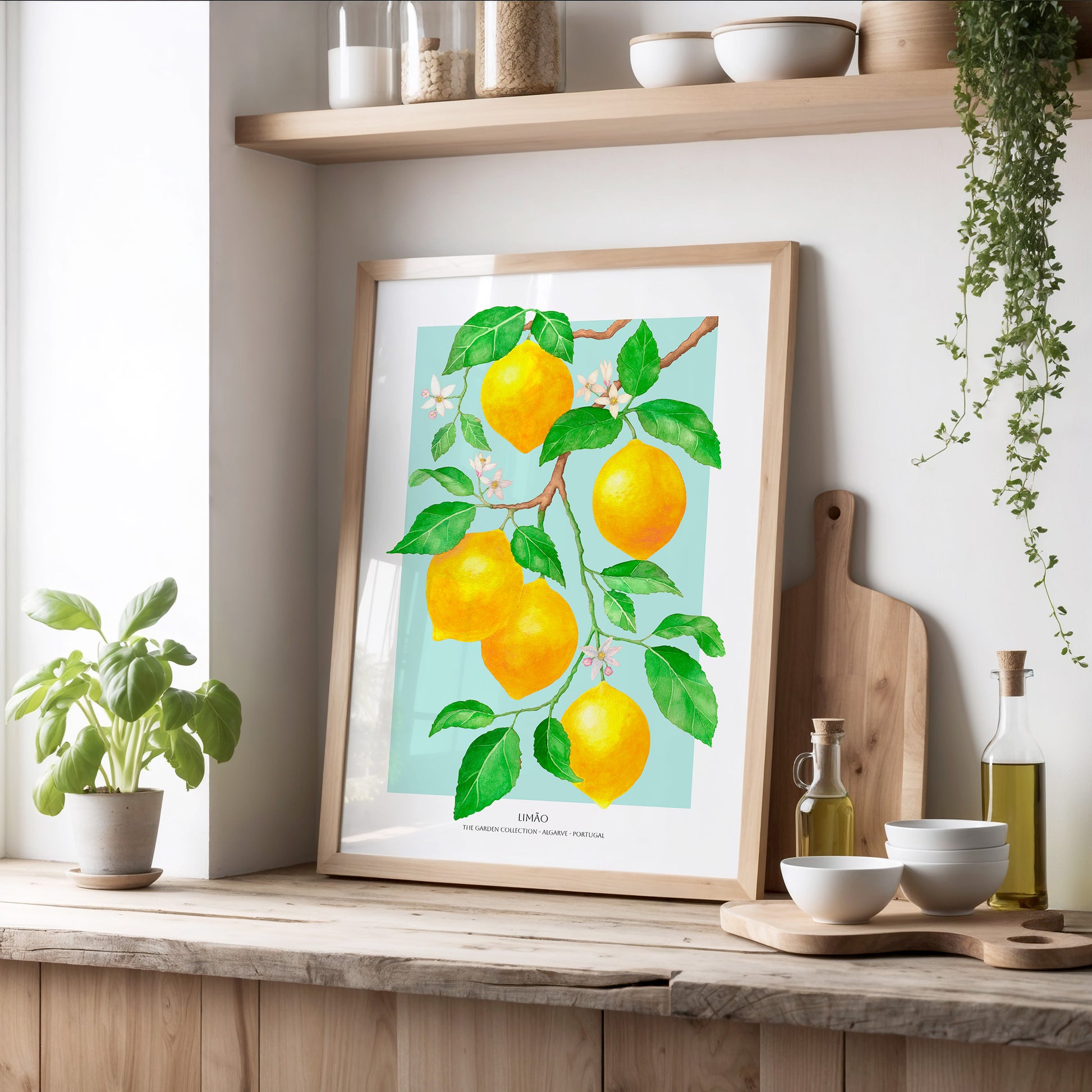 Framed artwork of lemons on a kitchen counter with plants and kitchen items.