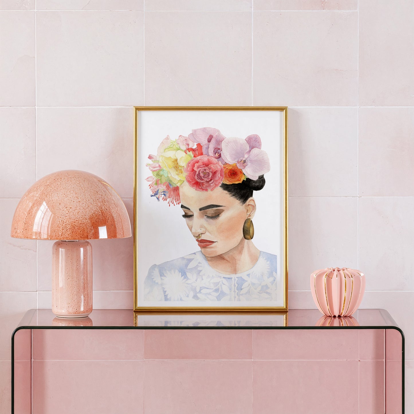 Framed artwork of a woman with flowers in her hair on a pink console table with a lamp and vase.
