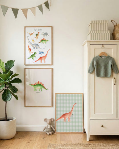 A styled children's room corner with framed dinosaur wall art hanging on a white wall, a potted fiddle-leaf fig plant, a small stuffed animal, a cream cabinet with a green sweater, and a basket on top.