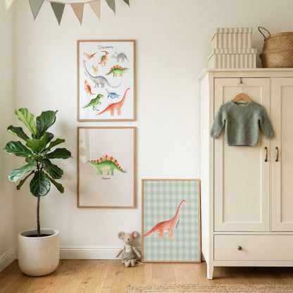A styled children's room corner with framed dinosaur wall art hanging on a white wall, a potted fiddle-leaf fig plant, a small stuffed animal, a cream cabinet with a green sweater, and a basket on top.