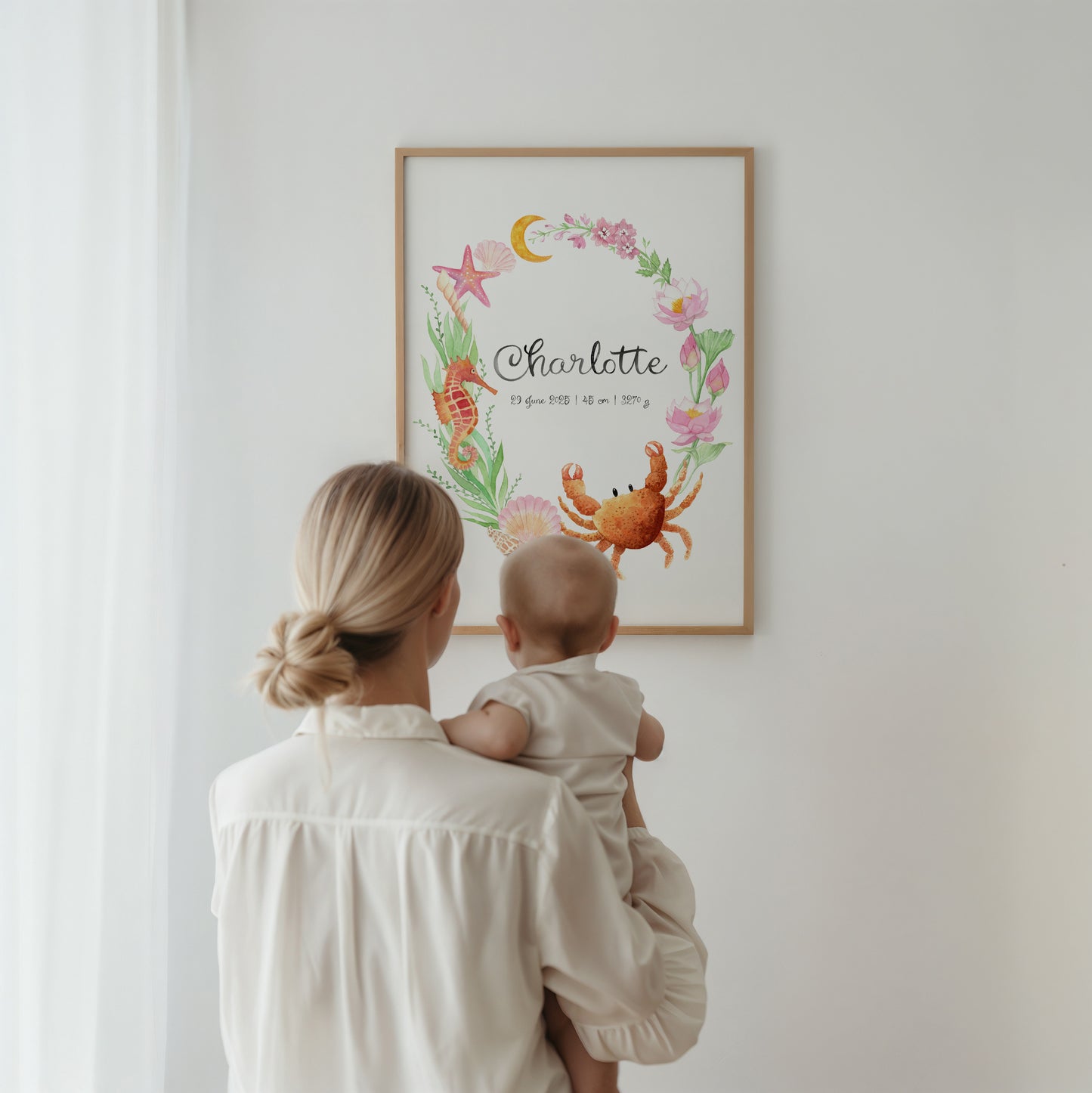 Woman holding a baby looking at a framed artwork on a wall