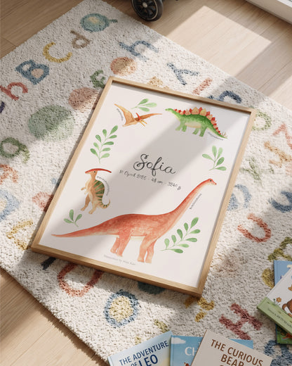 A framed personalized dinosaur art print with watercolor illustrations of dinosaurs and the name 'Sofia' in the center, styled on a colorful alphabet rug on a wooden floor.