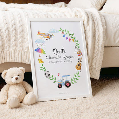 Framed baby milestone chart with illustrations of toys and text, placed on a carpeted floor with a teddy bear beside it.