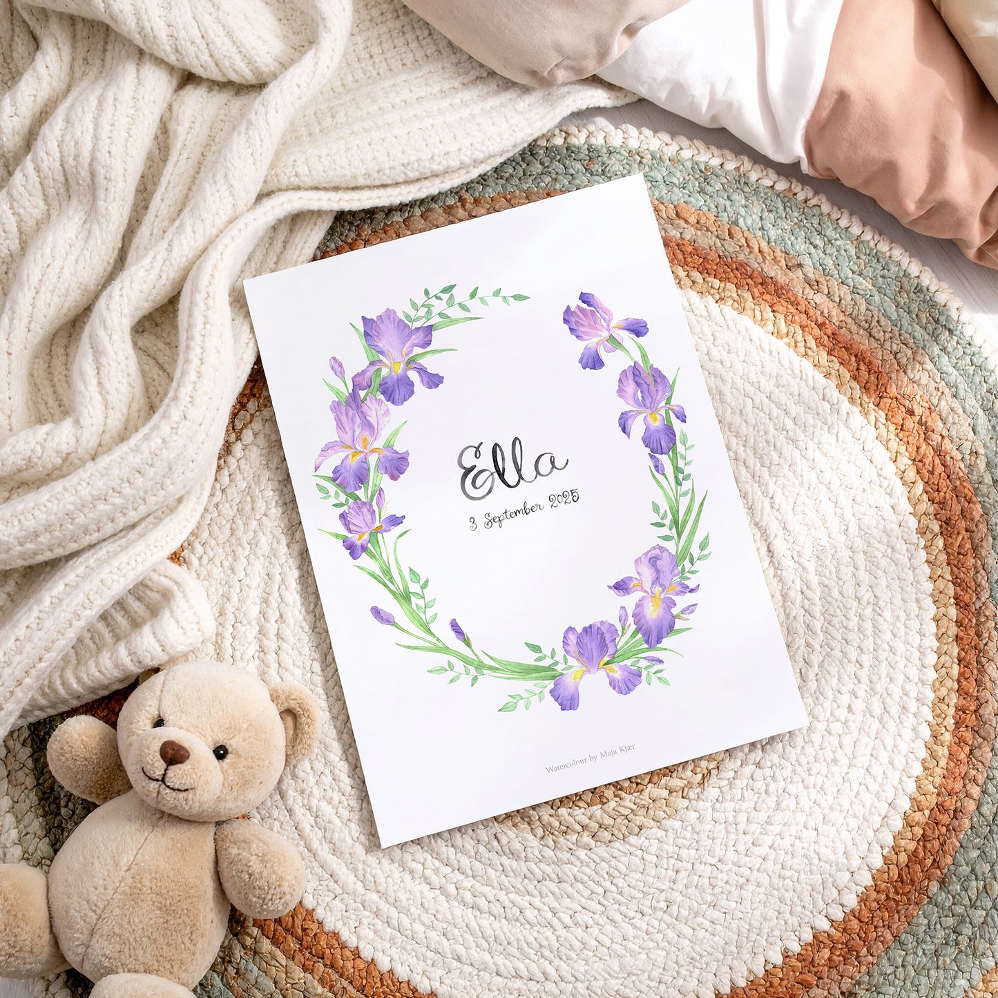 Poster with floral design and 'Ella' text on a textured surface with a teddy bear.