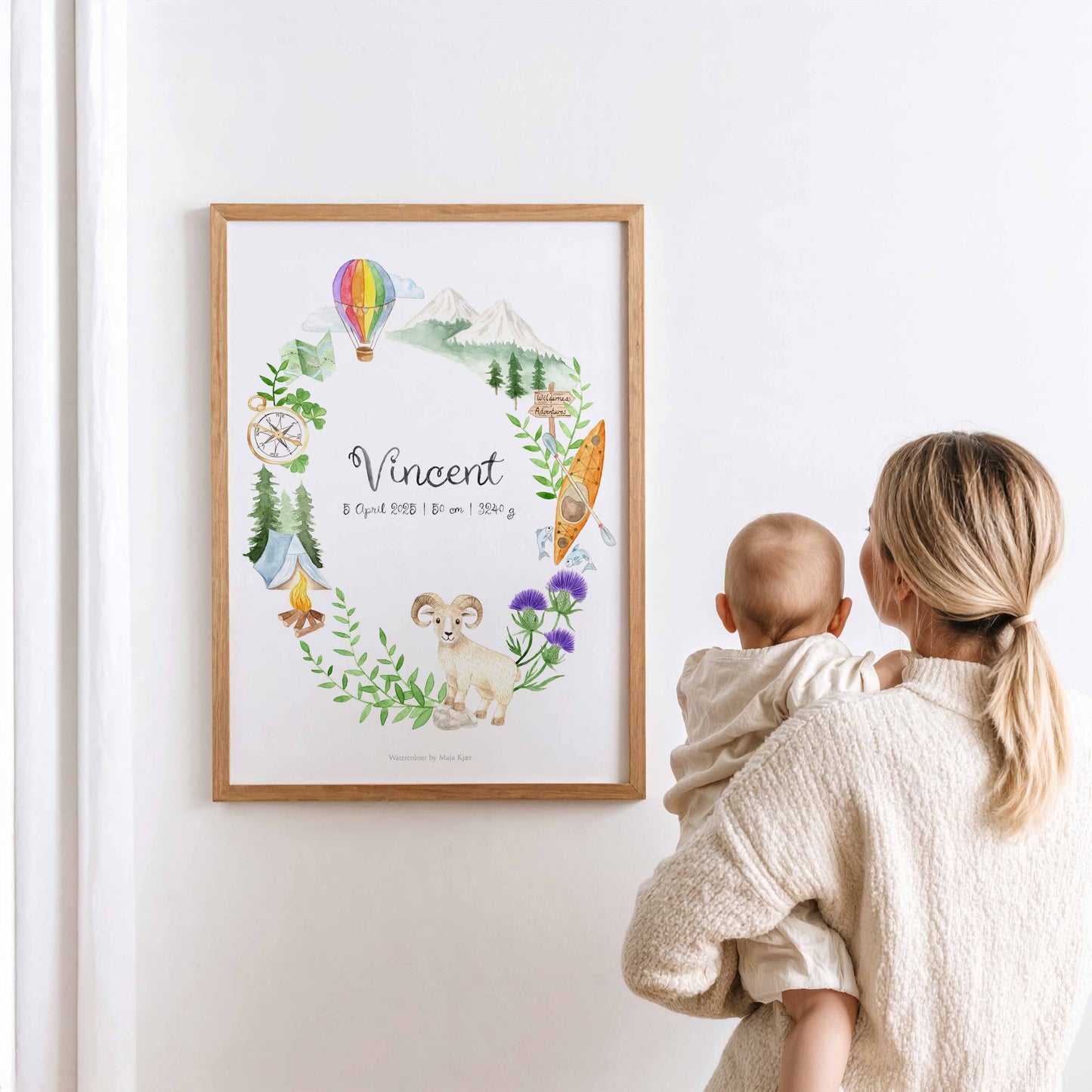Woman holding a baby looking at a framed zodiac poster for Aries with baby name and birth details
