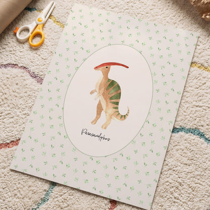 A square art print featuring a painted Parasaurolophus dinosaur in the center, surrounded by a white oval and a light green patterned border. The print is styled on a textured beige rug with craft scissors and a cardboard tube nearby.