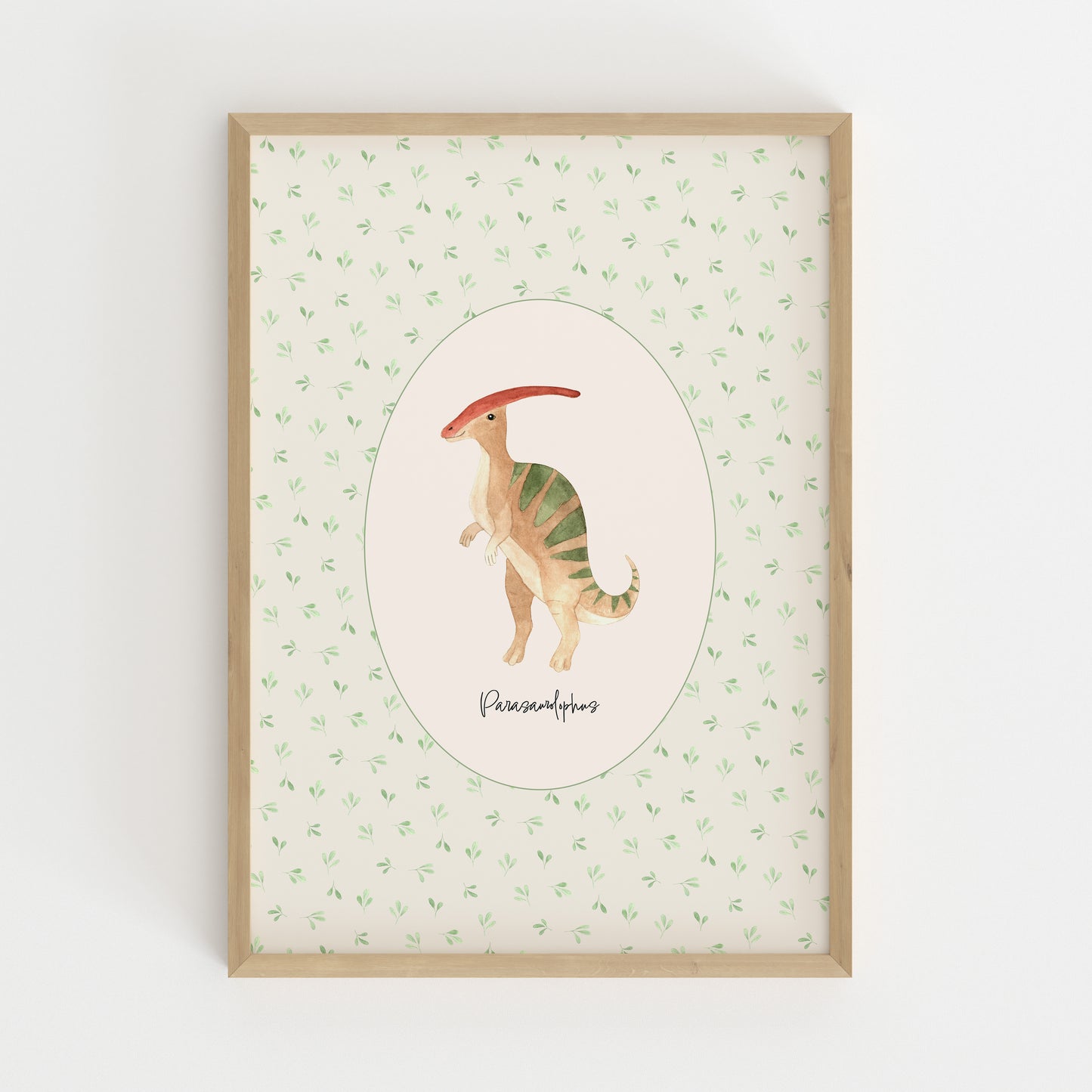 A framed art print featuring a watercolor illustration of a Parasaurolophus dinosaur in the center, surrounded by a light green leaf pattern on a cream background, enclosed in a natural wood frame.