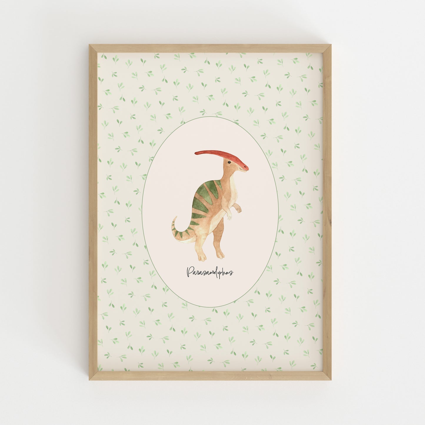 A framed children's art print featuring a watercolor illustration of a Parasaurolophus dinosaur inside an oval, set against a light green patterned background with a light wood frame.