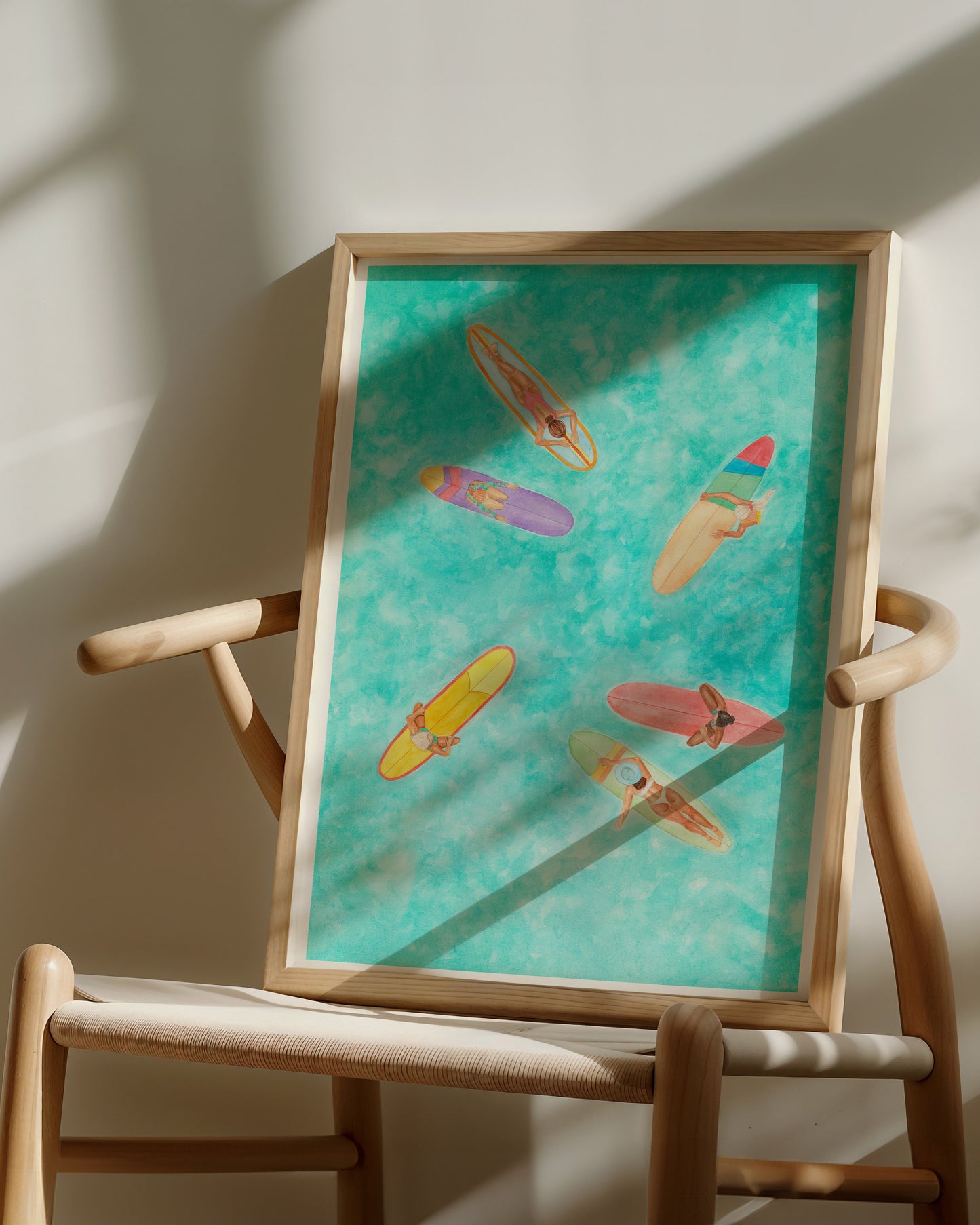 Framed artwork with colorful surfboards on a chair against a white wall