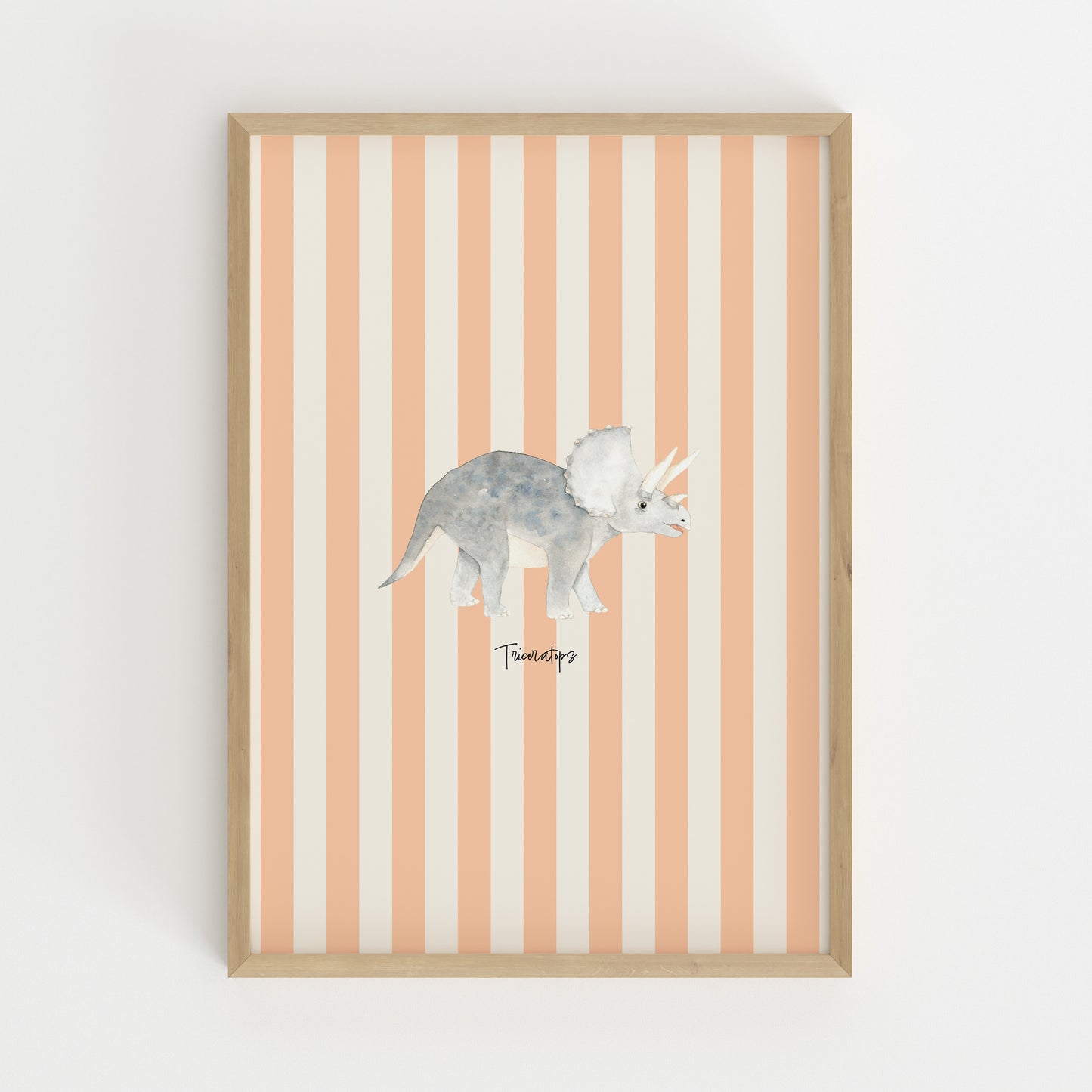 A framed wall art print featuring a watercolor-style gray Triceratops dinosaur centered on vertical peach and off-white stripes, set in a light natural wood frame against a white wall.