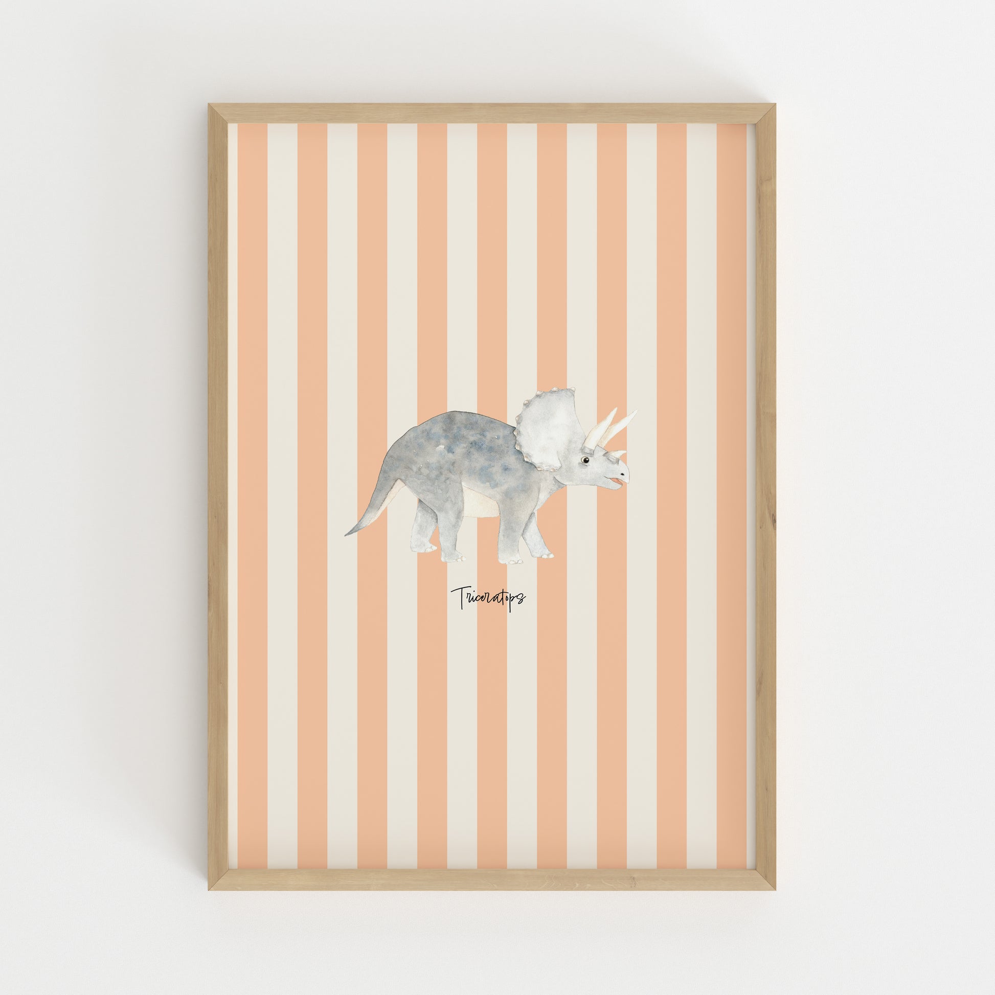 A framed wall art print featuring a watercolor-style gray Triceratops dinosaur centered on vertical peach and off-white stripes, set in a light natural wood frame against a white wall.
