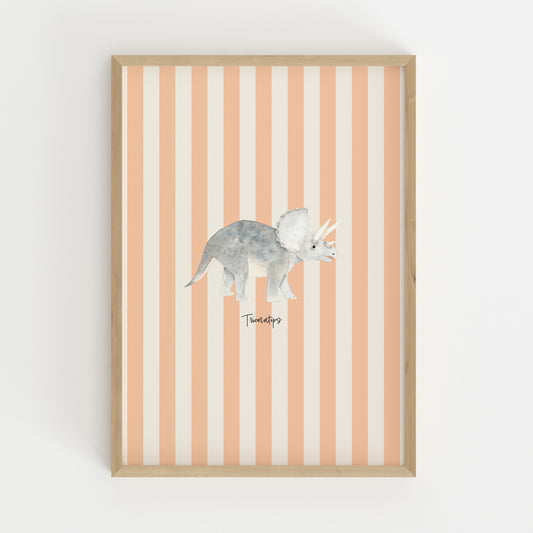 A framed wall art print featuring a watercolor-style gray Triceratops dinosaur centered on vertical peach and off-white stripes, set in a light natural wood frame against a white wall.