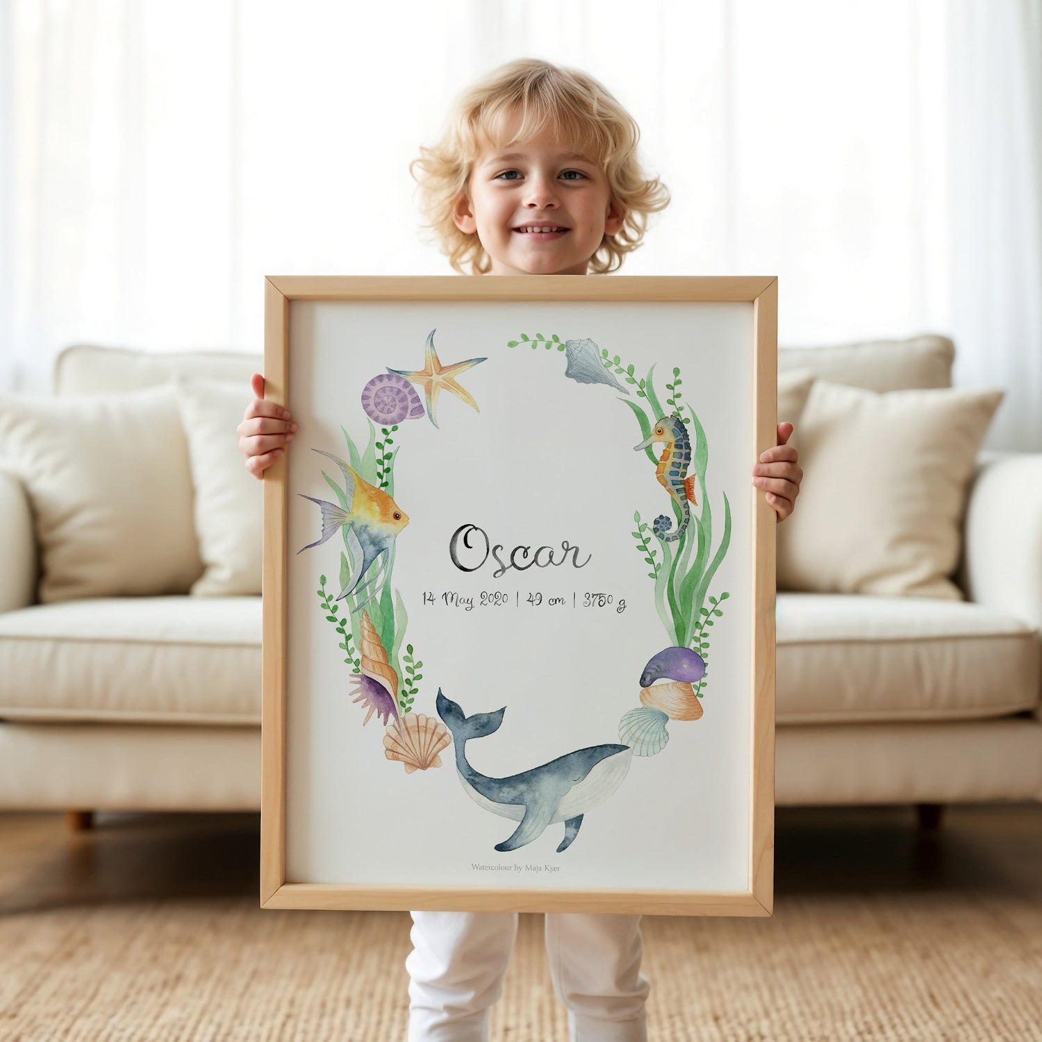 Child holding a framed name poster with whale in a living room